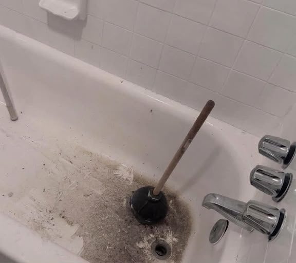 Before cleaning: a bathtub with a plunger and visible grime